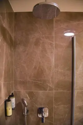 a bathroom with a shower with a stone wall at Casa Novi Dorcol Belgrade in Belgrade