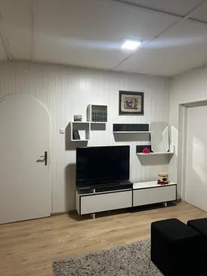 a living room with a flat screen tv and shelves at Apartman Riven in Borča
