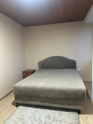 a bed in a bedroom with a white wall at Apartman Riven in Borča