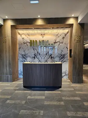 a lobby with a reception desk in front of a marble wall at Casa Novi Dorcol Belgrade 2 in Belgrade