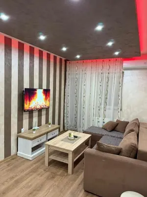 a living room with a couch and a tv on a wall at Perisic Apartman Obrenovac, sa parkingom in Obrenovac