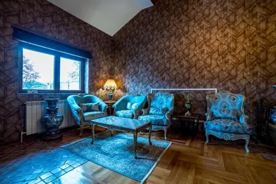 a living room with blue chairs and a table at Alrawda Resort in Risti°i