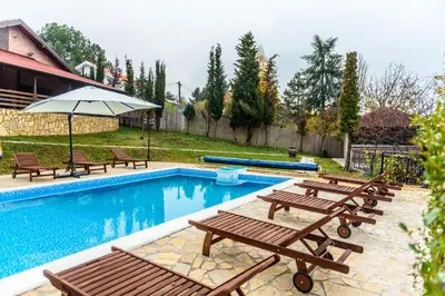 a pool with picnic tables and an umbrella at Alrawda Resort in Risti°i