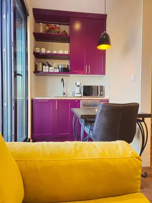 a kitchen with purple cabinets and a yellow couch at Sky Terrace Belgrade in Belgrade