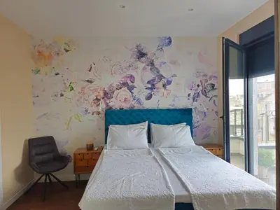 a bedroom with a bed with a blue headboard and a chair at Sky Terrace Belgrade in Belgrade