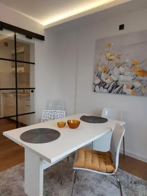 a white dining room table with two chairs and a painting at Fiore in Belgrade