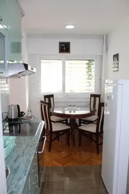 a kitchen with a table and chairs in a kitchen at TenMinutesToCenter Apartment in Belgrade