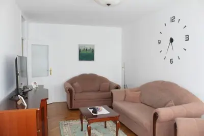 a living room with two couches and a clock on the wall at TenMinutesToCenter Apartment in Belgrade