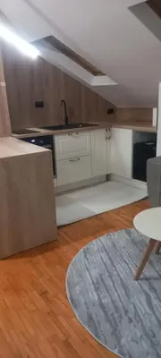 a kitchen with white cabinets and a table and a rug at Naru in Belgrade