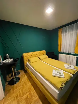 a bedroom with a yellow bed with a green wall at Apartman Hram in Belgrade