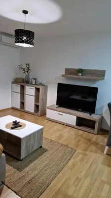 a living room with a flat screen tv and a table at Finans2 in Ruma