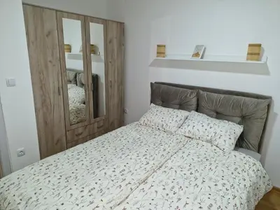 a bedroom with a bed with a wooden headboard and a mirror at Finans2 in Ruma