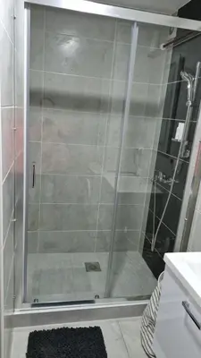 a shower with a glass door in a bathroom at Finans2 in Ruma