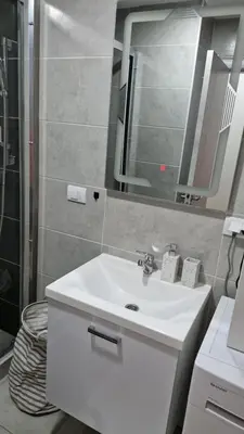 a bathroom with a white sink and a mirror at Finans2 in Ruma