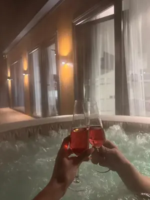 a person holding two glasses of wine in a bath tub at Elysium Garden in Belgrade