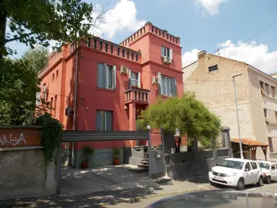 a red building with a white car parked in front of it at Guest House Miss Depolo in Belgrade