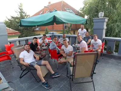 a group of people sitting around a table on a patio at Guest House Miss Depolo in Belgrade