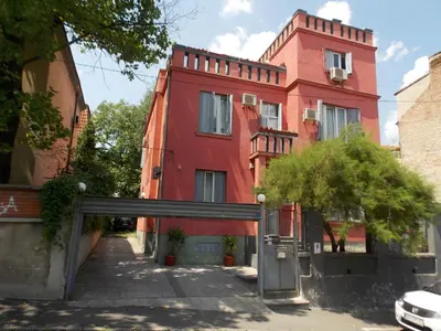 a red building with a gate in front of it at Guest House Miss Depolo in Belgrade