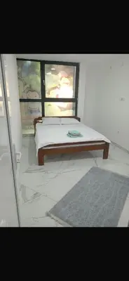 a bed in a room with a window and a rug at melvina 3 in Pančevo