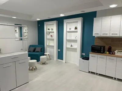 a kitchen with white cabinets and a blue wall at Modern studio in center of Belgrade in Belgrade