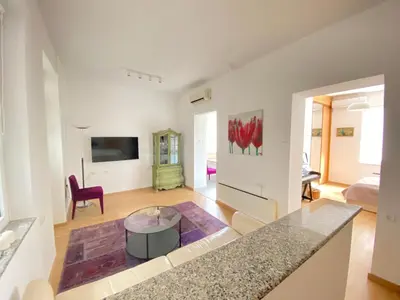 a kitchen and living room with a table and a couch at City center salon-style apartment free parking in Belgrade