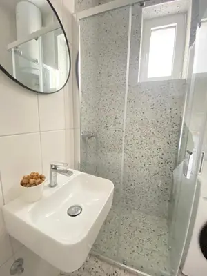 a bathroom with a shower and a sink and a mirror at City center salon-style apartment free parking in Belgrade