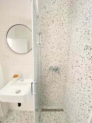 a bathroom with a shower with a sink and a mirror at City center salon-style apartment free parking in Belgrade