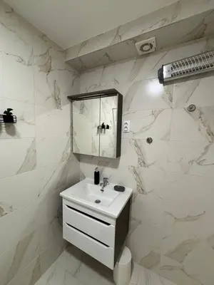 a white bathroom with a sink and a mirror at Apartmani IDILA in Smederevo