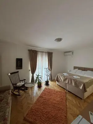a bedroom with a bed and a chair and a window at Apartmani IDILA in Smederevo