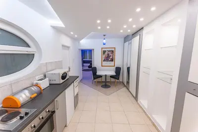 a kitchen with white cabinets and a table and chairs at Dove's Nook - A Stylish City Center Retreat in Belgrade