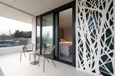 a room with chairs and a bedroom on a balcony at New Belgrade Premium Hotel in Belgrade