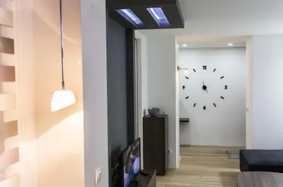 a living room with a tv and a clock on the wall at Apartment Nevena in Belgrade