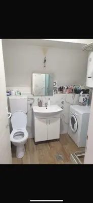 a bathroom with a toilet and a sink and a washing machine at Apartman- Ledine in Ledine
