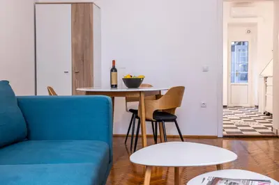a living room with a blue couch and a table at Black & White Delight in Belgrade