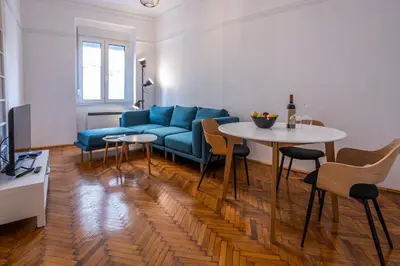 a living room with a blue couch and a table at Black & White Delight in Belgrade