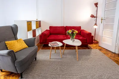 a living room with a red couch and a table at Elegant, Chique & Spacious Boho Loft in Belgrade