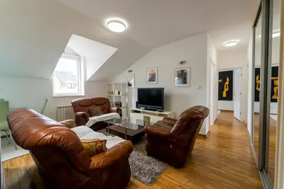 a living room with leather furniture and a flat screen tv at Spacious Family Apartment in Belgrade