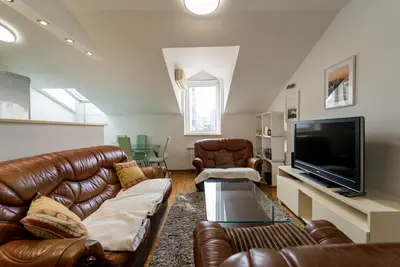 a living room with leather furniture and a flat screen tv at Spacious Family Apartment in Belgrade