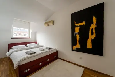 a bedroom with a bed and a painting on the wall at Spacious Family Apartment in Belgrade