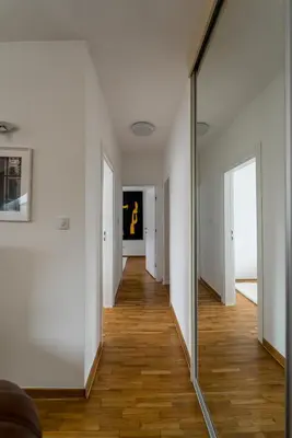 a mirror in a hallway with white walls and wood floors at Spacious Family Apartment in Belgrade