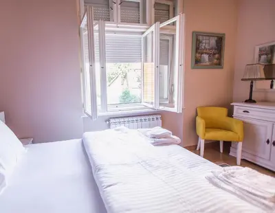 a bedroom with a bed and a yellow chair at Crown Apartment - Your Royal Stay in Belgrade