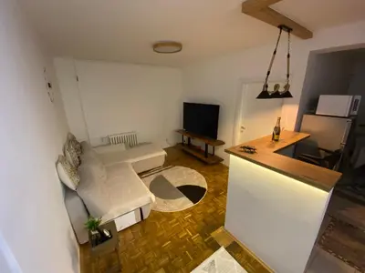 a living room with a white couch and a kitchen at Prestige in Belgrade