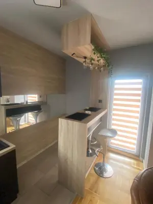 a kitchen with a counter and a table and a stool at Apartman LIMA in Belgrade