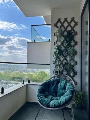 a green chair sitting on a balcony with a window at Sunny Nest in Belgrade
