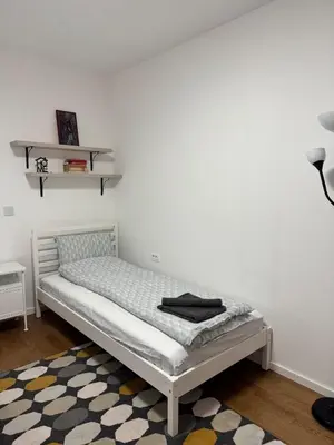 a bed in a room with a white wall at Sunny Nest in Belgrade