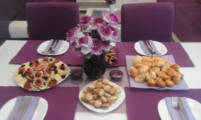 a table with plates of food and a vase of flowers at Apartment Avala in Belgrade