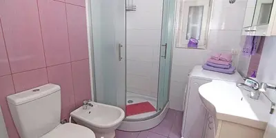 a pink bathroom with a shower and a toilet and a sink at Apartment Avala in Belgrade