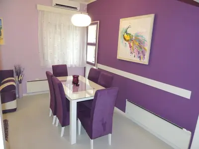 a purple dining room with a white table and purple chairs at Apartment Avala in Belgrade