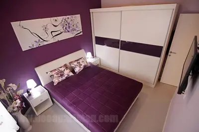a small bedroom with a purple bed and purple walls at Apartment Avala in Belgrade