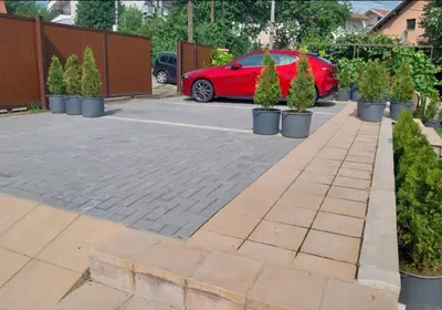 a red car parked in a parking lot with potted trees at New Belgrade Apartman - Near the Airport in Belgrade